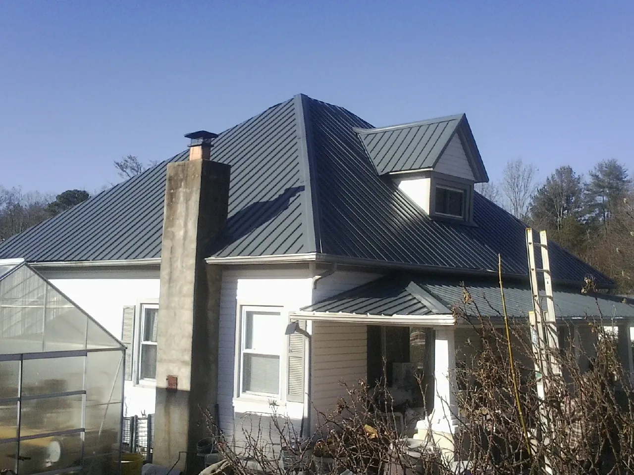 Dark blue standing seam metal roof on a white farmhouse with dormer — Slate & Tile Roof Repair by Roofing Brothers in Bethel